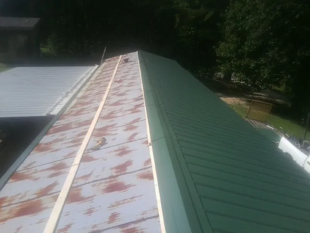Old rusted panels beside newly installed green metal roofing — Wind Damage Roof Repair by Roofing Brothers in Merritt Island