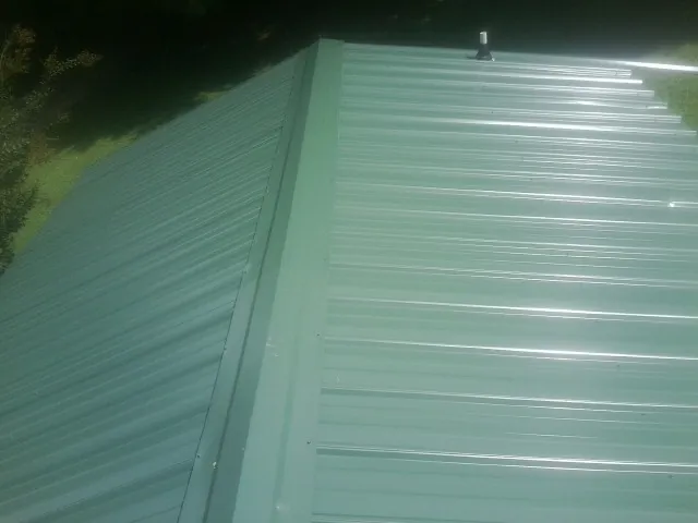 New green metal panels meeting at the ridge of a roof — Flat Roof Repair work by our crew in Merritt Island