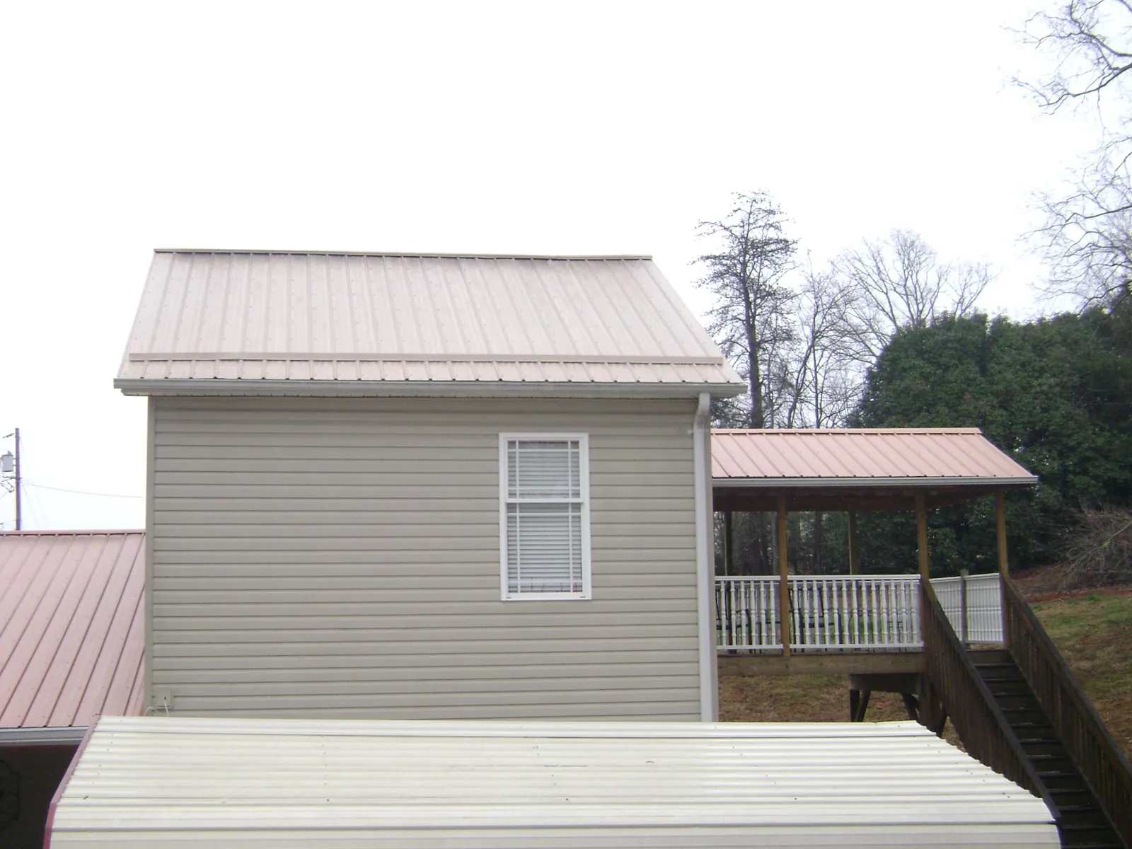 Tan metal roofs on a two story addition and attached porch, from a Roof Replacement job in Merritt Island