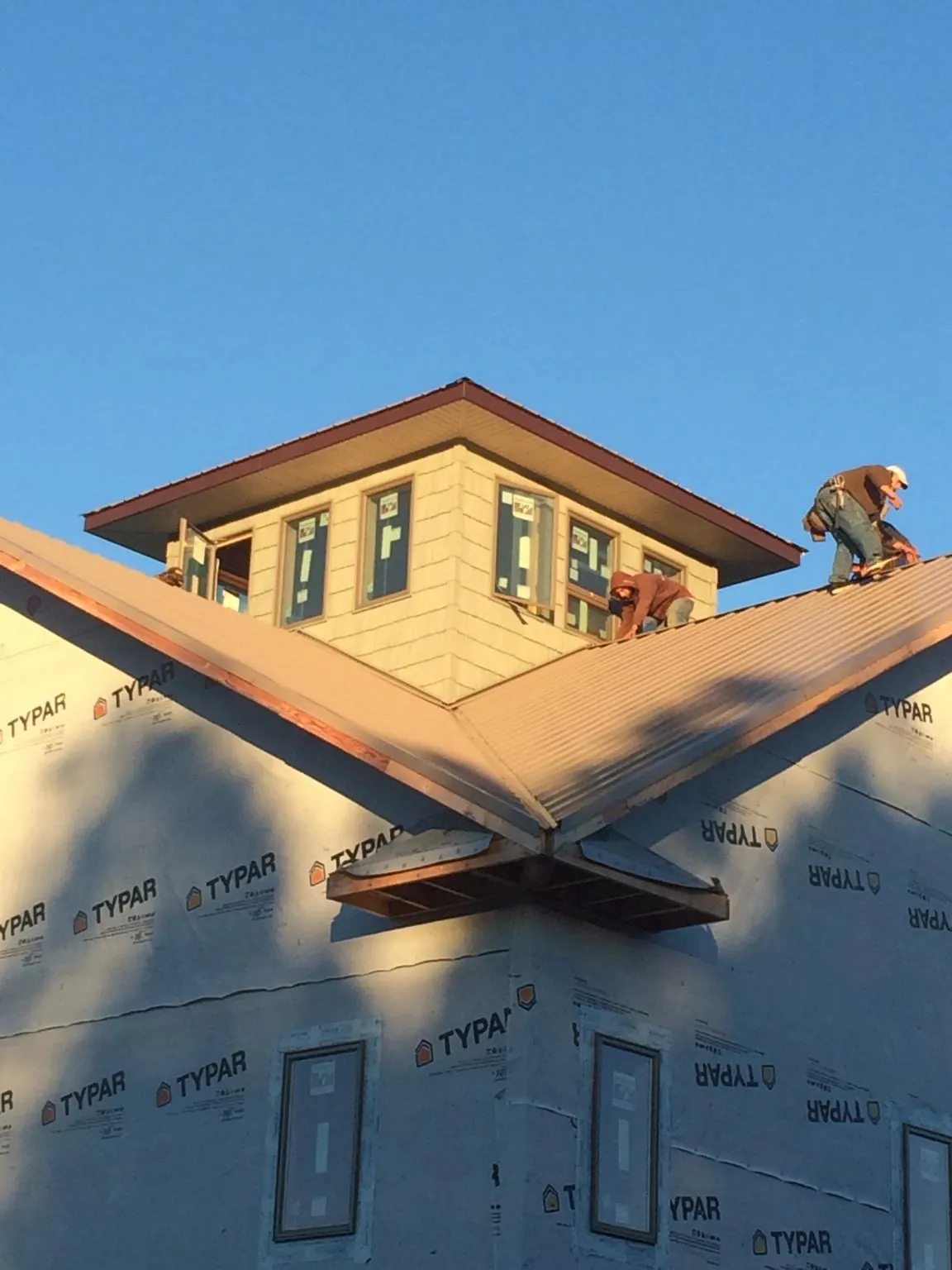 Roofers working around a rooftop cupola on a new metal roof at sunset — Roof Waterproofing in Merritt Island by Roofing Brothers